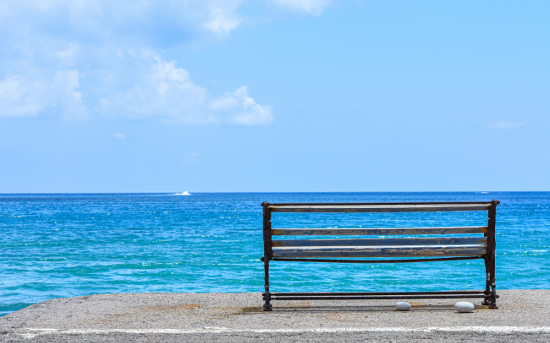 穏やかな海を前にしたベンチと、やわらかな光が差し込む風景