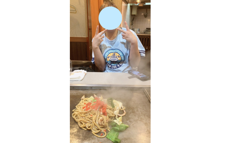 TUBEライブTシャツを着て焼きそばを楽しむ様子。熱気と湯気が立ちのぼる。