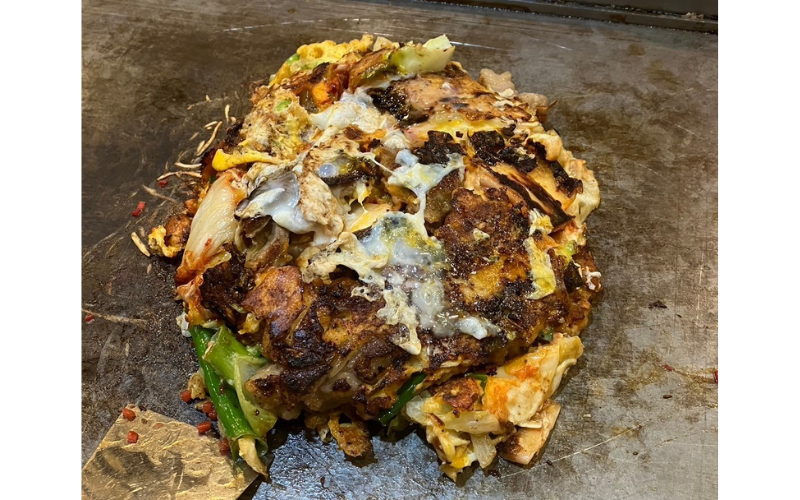 鉄板の上で焼き上げられた『チング』のお好み焼き。香ばしいソースの香りが食欲をそそる。
