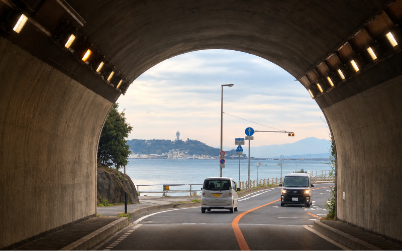 トンネルの出口から海と空が見える海沿いの道路